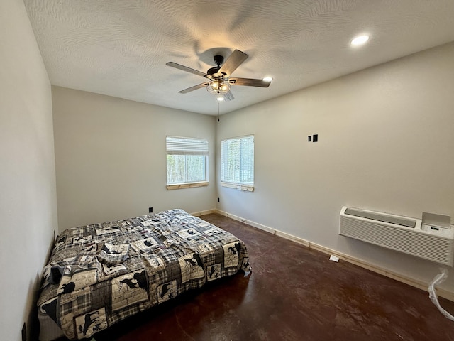 bedroom with a textured ceiling, a wall mounted air conditioner, a ceiling fan, and baseboards