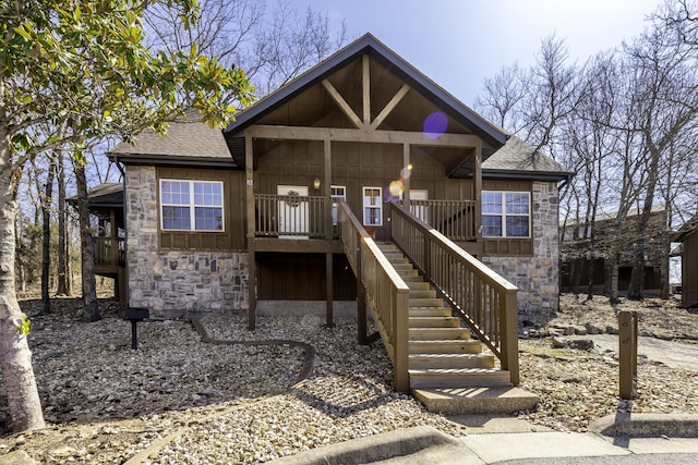 chalet / cabin with stone siding, a shingled roof, and board and batten siding