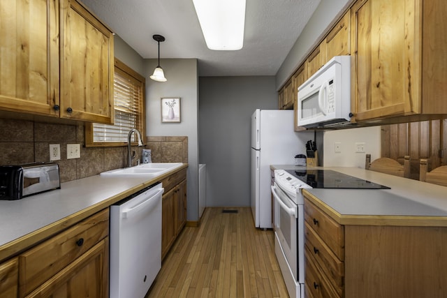 kitchen featuring white appliances, a sink, light countertops, light wood-type flooring, and tasteful backsplash