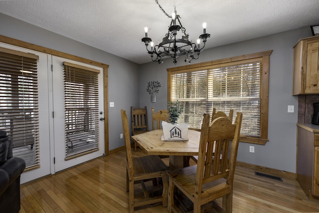 dining room with visible vents, a textured ceiling, a chandelier, and light wood-style flooring