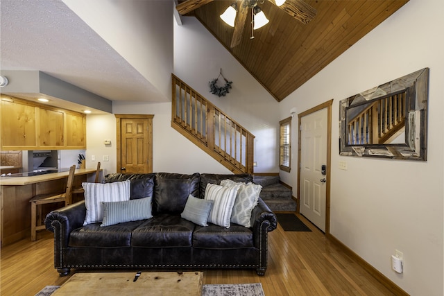 living area featuring wood ceiling, ceiling fan, high vaulted ceiling, light wood-type flooring, and stairs