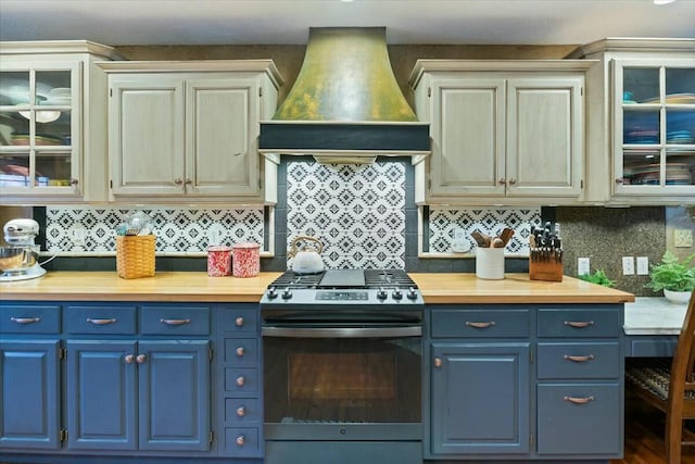 kitchen featuring blue cabinets, custom range hood, glass insert cabinets, and stainless steel gas range oven