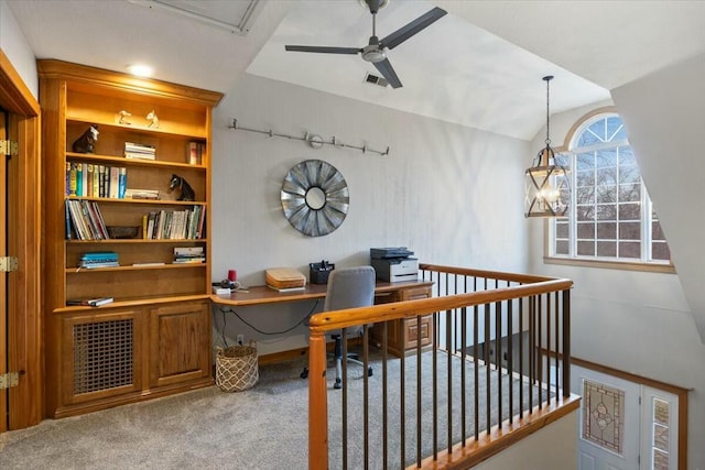 carpeted office featuring lofted ceiling, ceiling fan, visible vents, and built in desk