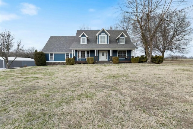 cape cod-style house with roof with shingles, a porch, and a front yard