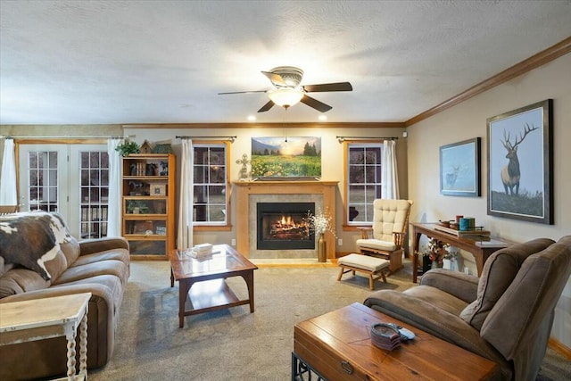 carpeted living room featuring crown molding, a fireplace with flush hearth, a ceiling fan, a textured ceiling, and baseboards