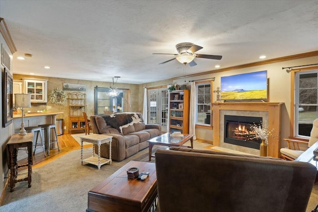 living room featuring recessed lighting, a textured ceiling, crown molding, and a glass covered fireplace