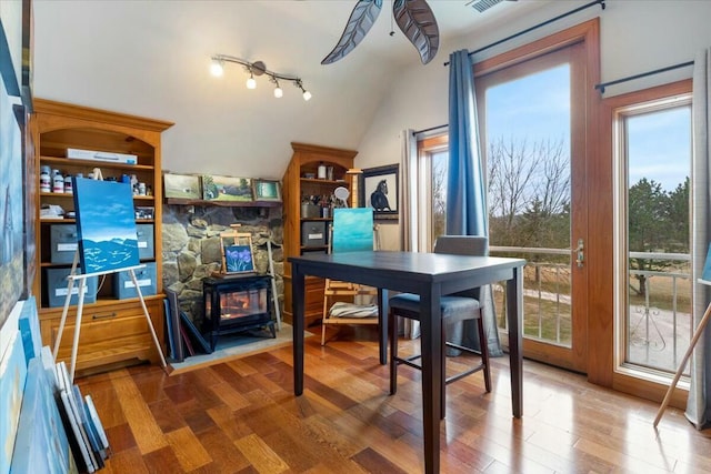 interior space featuring lofted ceiling, visible vents, wood finished floors, and a wood stove