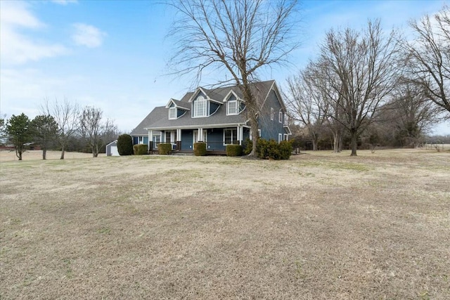 new england style home with a porch, an outbuilding, and a front yard