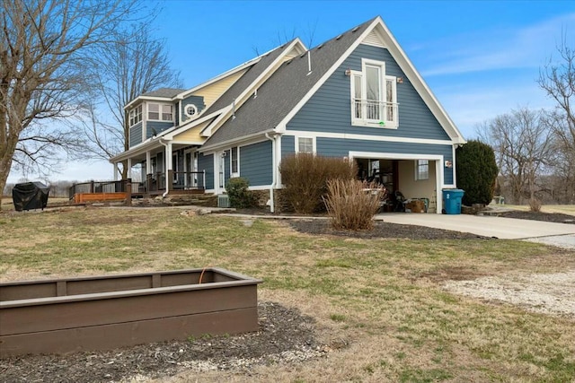 view of side of property with covered porch, concrete driveway, and a lawn