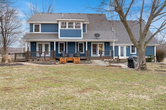 back of property with a shingled roof, french doors, covered porch, and a lawn