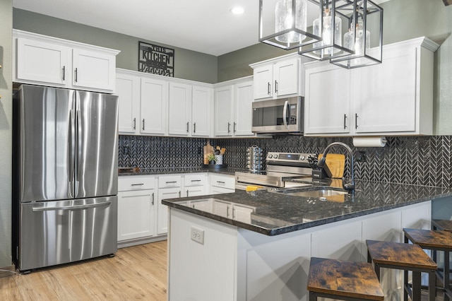 kitchen with dark stone counters, appliances with stainless steel finishes, a sink, and white cabinetry