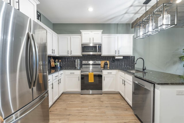 kitchen with light wood finished floors, stainless steel appliances, backsplash, white cabinets, and a sink