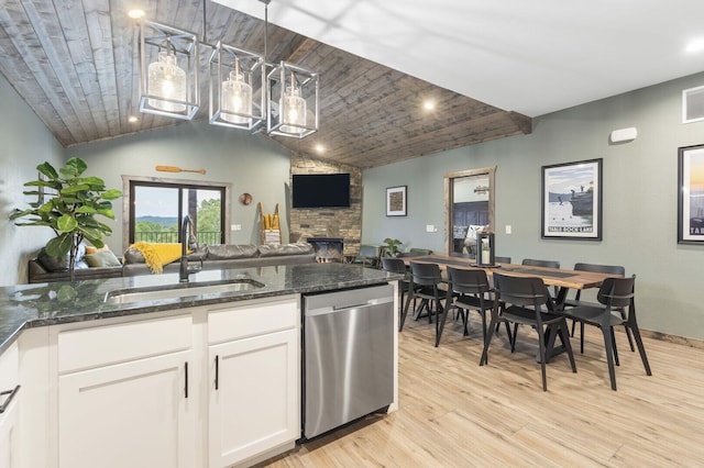 kitchen featuring a fireplace, light wood finished floors, open floor plan, a sink, and dishwasher