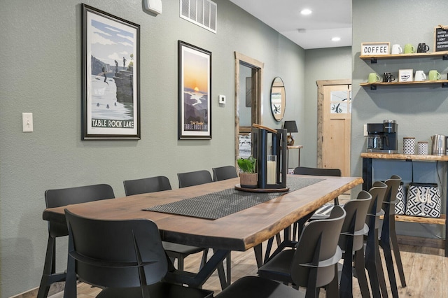 dining area featuring light wood-type flooring, a textured wall, visible vents, and recessed lighting