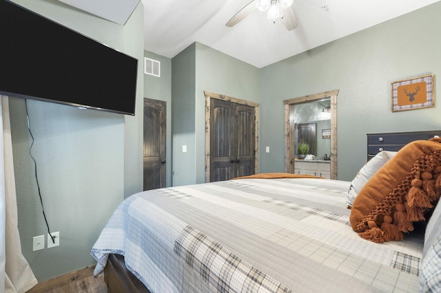 bedroom with connected bathroom, visible vents, ceiling fan, and wood finished floors