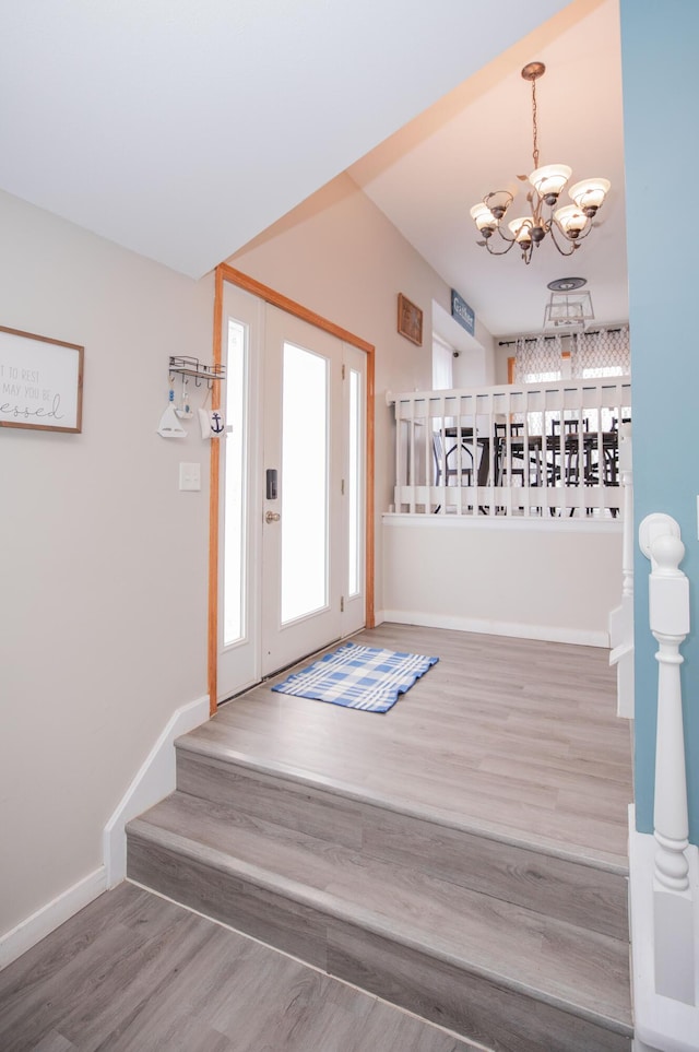 entryway featuring a chandelier, stairway, baseboards, and wood finished floors