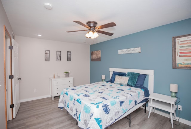 bedroom with ceiling fan, baseboards, and wood finished floors