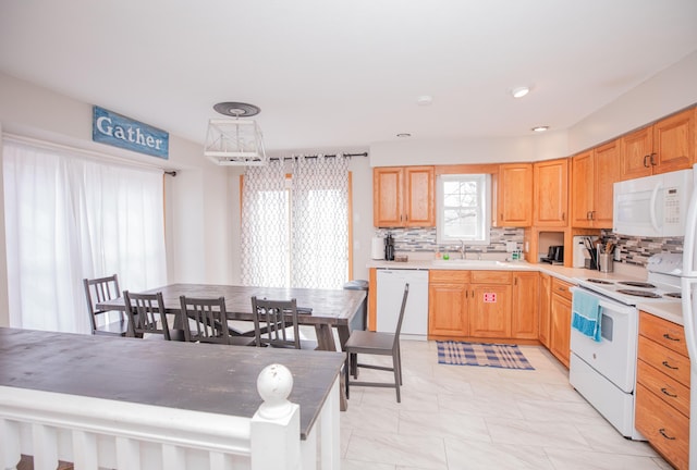 kitchen with white appliances, tasteful backsplash, light countertops, light brown cabinets, and a sink