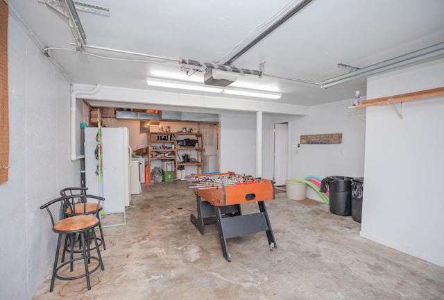 garage featuring washing machine and dryer, a garage door opener, and freestanding refrigerator