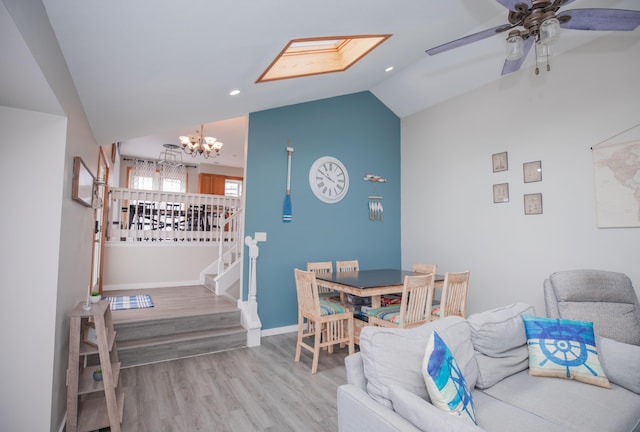 dining area with baseboards, stairway, wood finished floors, vaulted ceiling, and ceiling fan with notable chandelier