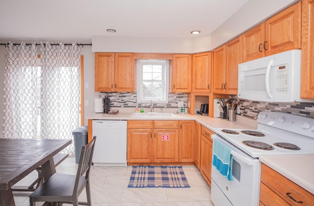 kitchen with white appliances, decorative backsplash, light countertops, and a sink