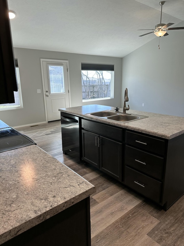 kitchen featuring dishwashing machine, dark cabinetry, a sink, and light wood-style floors