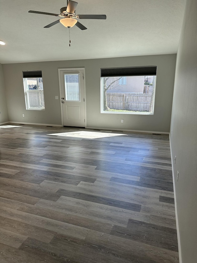 empty room with plenty of natural light, baseboards, and dark wood-type flooring