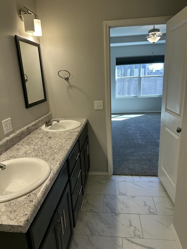 bathroom featuring marble finish floor, a sink, baseboards, and double vanity