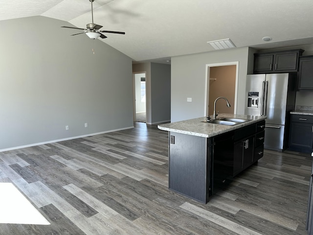 kitchen with a sink, a kitchen island with sink, open floor plan, and high end fridge