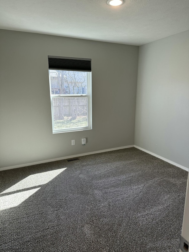 carpeted spare room with a textured ceiling and baseboards