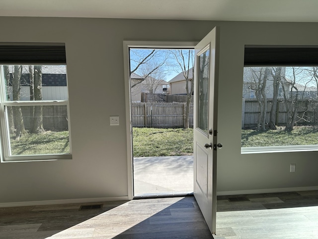 doorway featuring visible vents, baseboards, and wood finished floors