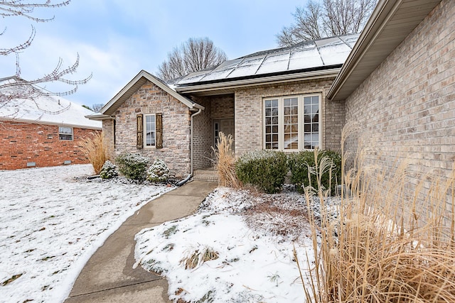 exterior space featuring stone siding, solar panels, and brick siding