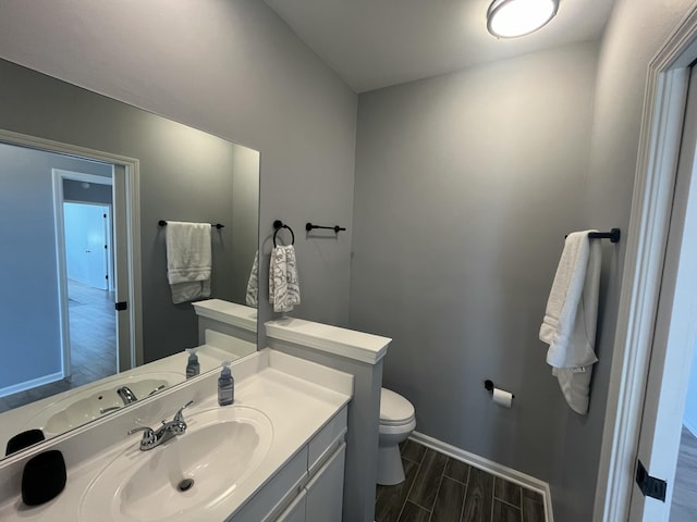 half bath featuring vanity, toilet, baseboards, and wood tiled floor