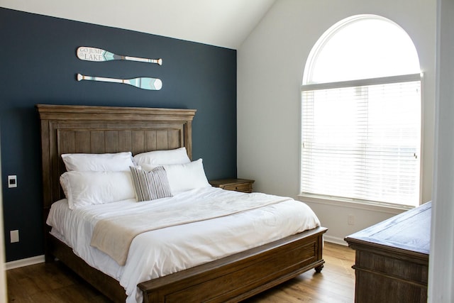 bedroom featuring baseboards, multiple windows, wood finished floors, and vaulted ceiling