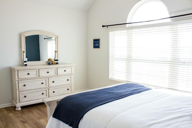 bedroom with baseboards, lofted ceiling, and wood finished floors