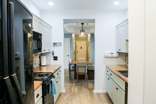 kitchen featuring decorative backsplash, black appliances, light wood-style floors, and wooden counters