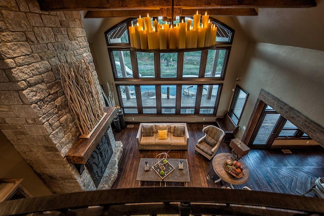 living area featuring hardwood / wood-style floors, beamed ceiling, and a towering ceiling