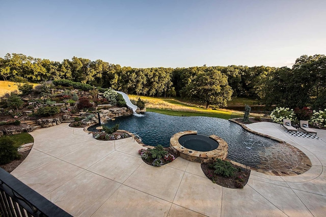 view of swimming pool featuring a patio, a water slide, and a pool with connected hot tub