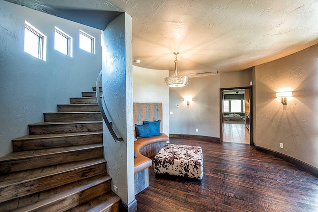 stairway with a textured wall, a textured ceiling, baseboards, and hardwood / wood-style flooring