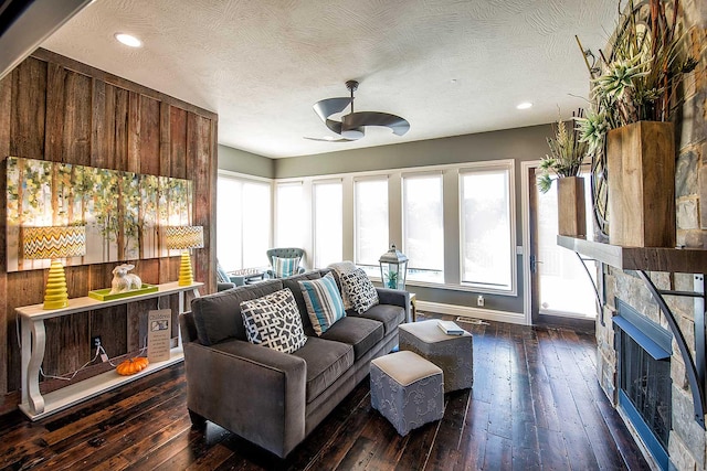 living area with a wealth of natural light, dark wood-style flooring, and a fireplace