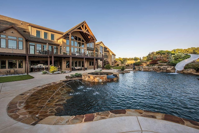 view of swimming pool with a water slide, a patio area, and a pool with connected hot tub