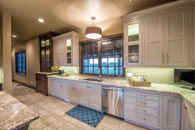 kitchen featuring tasteful backsplash, dishwasher, light stone counters, a sink, and recessed lighting