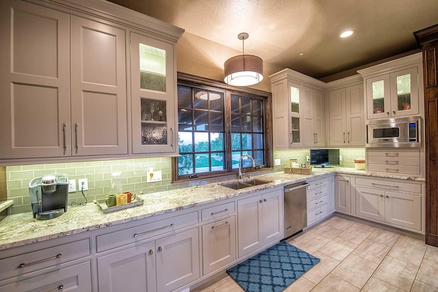 kitchen with tasteful backsplash, recessed lighting, appliances with stainless steel finishes, glass insert cabinets, and a sink