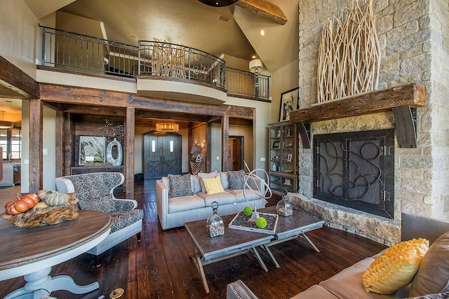 living area featuring high vaulted ceiling, wood-type flooring, and a stone fireplace