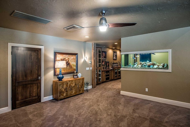 interior space with ceiling fan, visible vents, and baseboards