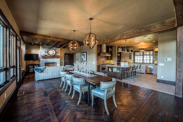 dining space featuring a large fireplace, parquet floors, beamed ceiling, and baseboards