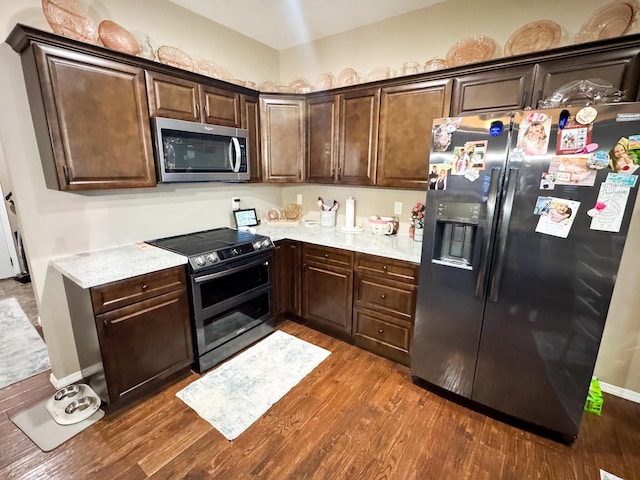 kitchen featuring dark brown cabinets, appliances with stainless steel finishes, light countertops, and dark wood-type flooring