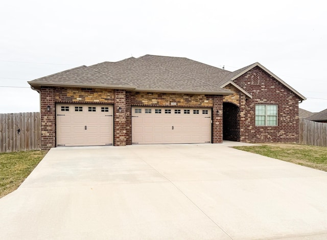 single story home featuring driveway, brick siding, fence, and roof with shingles