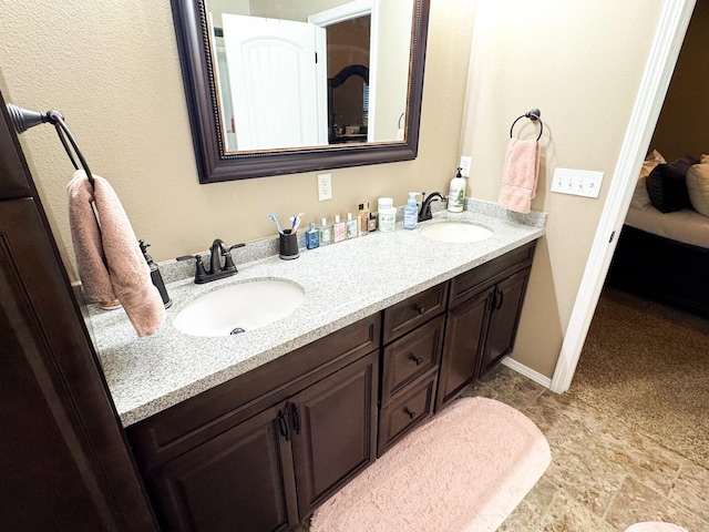 bathroom featuring a sink, baseboards, and double vanity