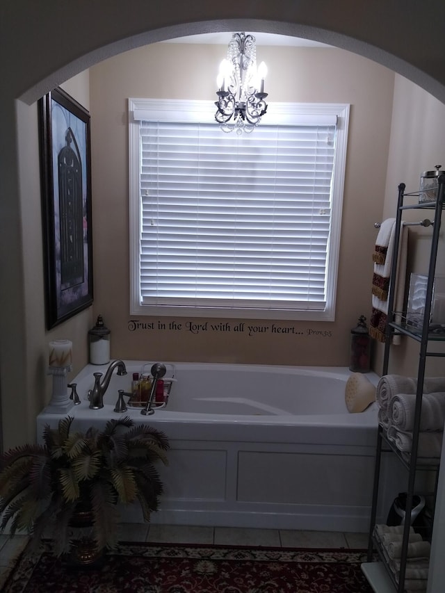 full bath featuring an inviting chandelier, a garden tub, and tile patterned floors